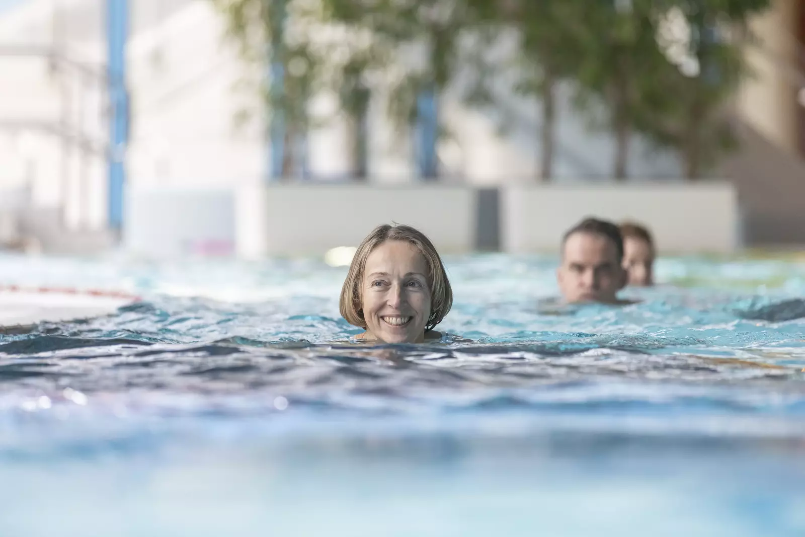 Schwimmen im Erlebnis-Innenbecken Eine Frau im Vordergrund einer Schwimmergruppe schwimmt im Erlebnis-Innenbecken im LEUZE