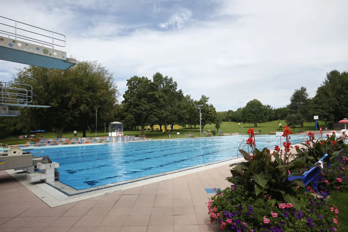 Mehrzweckbecken mit Sprungturm Freibad Möhringen Außenansicht Mehrzweckbecken ohne Badegäste mit Sprungturm und einer Blumenrabatte im Freibad Möhringen.