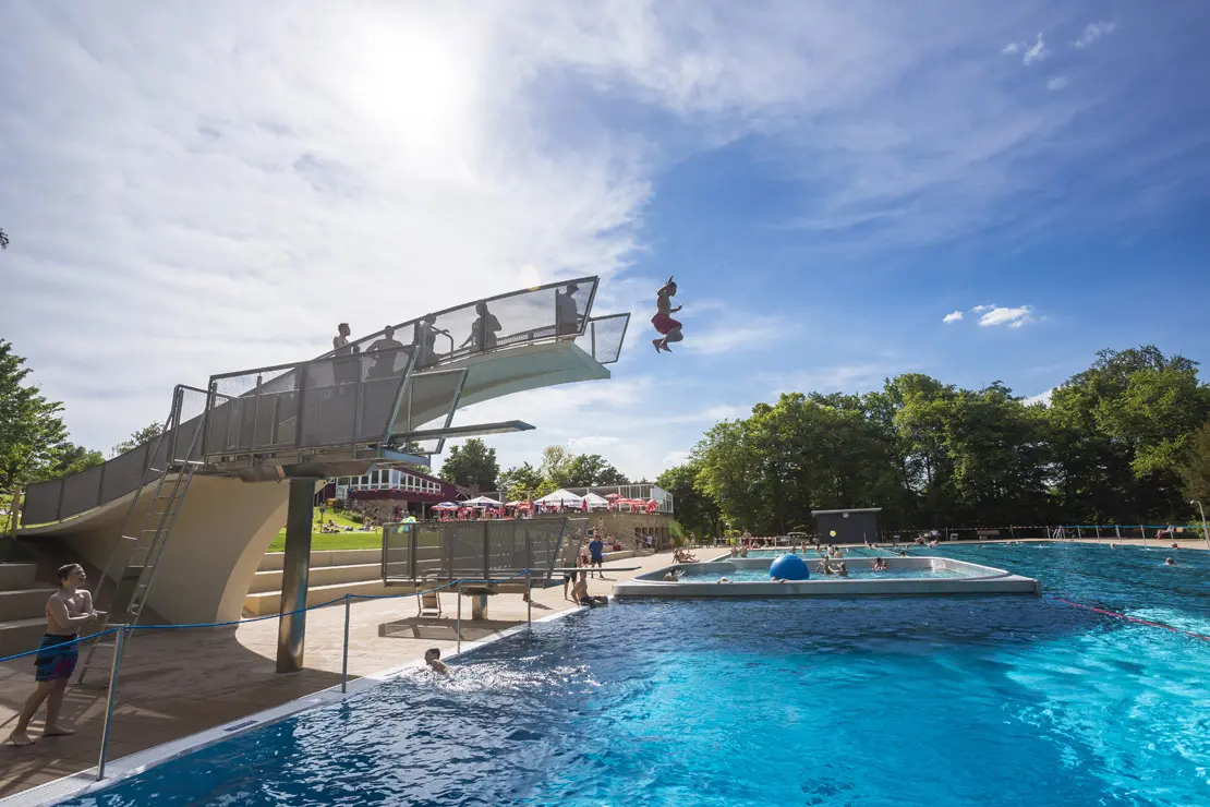 Ein Jügendlicher springt vom Sprungturm ins Schwimmbecken im Höhenfreibad Killesberg.
